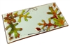 A rectangular tray of fused glass. Most of the glass is a light cream with a thin outer border of brown. A cluster of three different green and orange leaves are on each opposing diagonal, along with a few acorns, and decorative black lines.