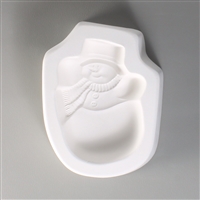 A roughly oval, white ceramic mold for fusing hot glass on a grey background. A snowman with a top hat, striped scarf, and two buttons has been carved into it. He is positioned with his arms raised up.