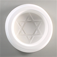 A circular, white ceramic mold for fusing hot glass on a grey background. A six-pointed Star of David inside a circle has been carved into it.