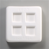 A square, white ceramic mold for fusing hot glass on a grey background. Four smaller squares, evenly spaced apart, have been carved into it. The mold has LF07 Squares engraved around the sides in print.