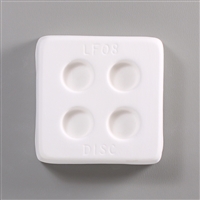 A square, white ceramic mold for fusing hot glass on a grey background. Four small circles, evenly spaced apart, have been carved into it. The mold has LF08 Disc engraved on the sides in print.