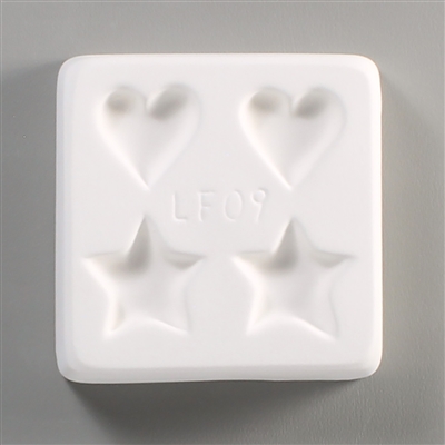 A square, white ceramic mold for fusing hot glass on a grey background. Two small hearts and two small stars, evenly spaced apart, have been carved into it, with the hearts at the top and stars at the bottom. The mold has LF09 engraved in the middle.