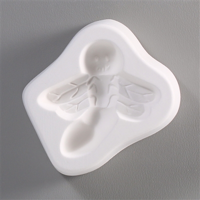 A roughly rectangular, white ceramic mold for fusing hot glass on a grey background. A stylized, cartoon-like firefly with a smile has been carved into it. Its body is slightly curved and its wings are angled downwards.