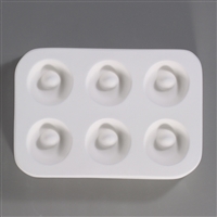 A rectangular, white ceramic mold for fusing hot glass on a grey background. Six evenly spaced circular rings with empty centers have been carved into it.