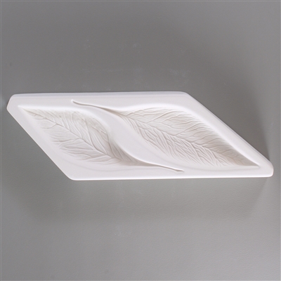 A parallelogram-shaped, white ceramic mold for fusing hot glass on a grey background. Two thin, detailed leaves pointing opposite directions have been carved into it.