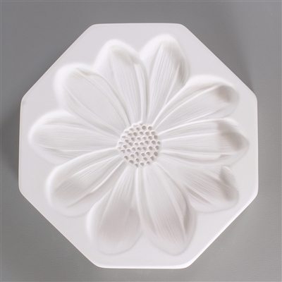 An octagonal, white ceramic mold for fusing hot glass on a grey background. A large, flat, detailed daisy flower with ten petals has been carved into it.