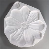 A roughly tear-shaped, white ceramic mold for fusing hot glass on a grey background. A large detailed flat daisy flower with ten petals has been carved into it. There is a small textured circle above the flower to make an extra center.