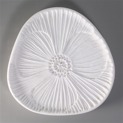 A rounded triangle-shaped, white ceramic mold for fusing hot glass on a grey background. A detailed flat poppy flower has been carved into it, occupying the entire space of the mold.