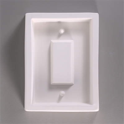 A rectangular, white ceramic mold for fusing hot glass on a grey background. A smaller rectangle has been carved into it.  There is a long, wide, raised rectangle in the center, and one protruding post above that center and one post below.