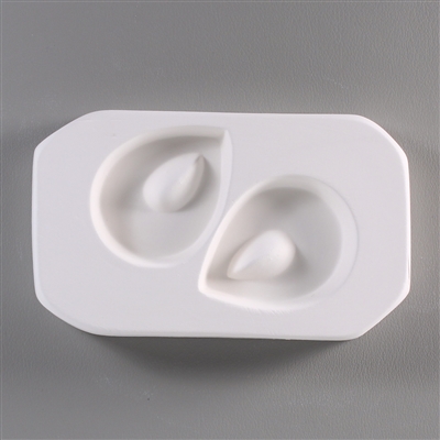 A roughly rectangular, white ceramic mold for fusing hot glass on a grey background. Two small, rounded tear shapes have been carved into it. Each tear has a smaller raised tear shape towards the top through which a string can pass after fusing.