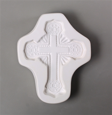 A cross-shaped white ceramic mold for fusing hot glass on a grey background. An ornate and intricately designed cross has been carved into it.