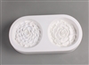 An oval-shaped white ceramic mold for fusing hot glass on a grey background. Two detailed round flat succulents have been carved into it. The right succulent is slightly larger, and has fewer but wider petals than the left.