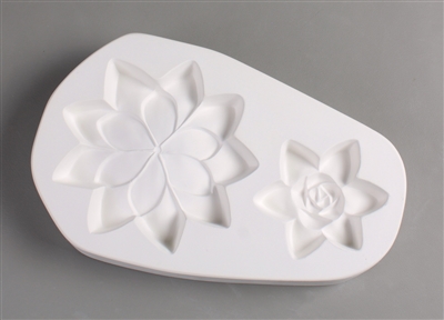 An oval-shaped white ceramic mold for fusing hot glass on a grey background. Two detailed flat succulents have been carved into it. The left succulent is larger with a simpler center, but both have pointed petals.