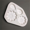 A roughly triangular white ceramic mold for fusing hot glass on a grey background. Two small daisy flowers and two teardrop leaves have been carved into it. The daisies are different sizes with similar designs, and the leaves are about the same.