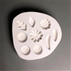 A roughly circular white ceramic mold for fusing hot glass on a grey background. An assortment of small flowers and leaves have been carved into it. There are two daisies, a rose, a mum, a zinnia, and four separate shapes of leaf.