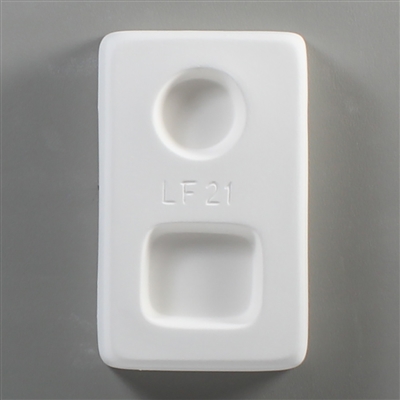 A rectangular white ceramic mold for fusing hot glass on a grey background. One small circle and one small square have been carved into it. The circle is above the square, and LF21 is carved in print between them.