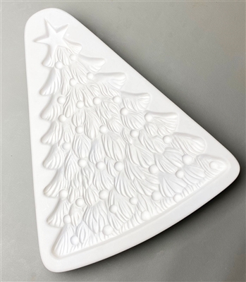 A triangular white ceramic mold for fusing hot glass on a grey background. A large, detailed Christmas tree topped with a five-point star has been carved into it. The tree has small round ornaments scattered around it.