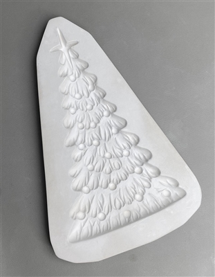 A triangular white ceramic mold for fusing hot glass on a grey background. A thin, detailed Christmas tree topped with a four-pointed star has been carved into it. The tree is covered in small circular ornaments.
