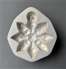 A white ceramic mold for fusing hot glass on a grey background. An eight-armed snowflake ornament with a faceted and geometric design has been carved into it. The top of the snowflake has a post to allow for hanging after fusing.