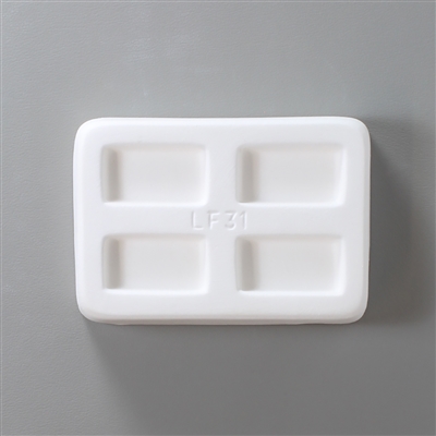 A rectangular white ceramic mold for fusing hot glass on a grey background. Four separate but identical rectangles have been carved into it with equal space between them. LF31 is carved onto the mold between them.