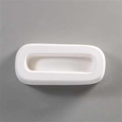 A rectangular white ceramic mold for fusing hot glass on a grey background. A long oval with flattened sides has been carved into it. The oval takes up most of the mold but there is a small border of empty space around it.