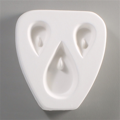 A white ceramic mold for fusing hot glass on a grey background. Three tears have been carved into it, one large on the bottom and two smaller above. There is a post towards the top of each tear allowing for the resulting piece to be strung as jewelry.