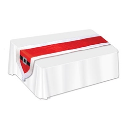 The Santa Suit Fabric Table Runner is red with white trim and at each end is a black belt with a silver glittery buckle and a white pom pom. It measures 13 inches wide and 5 feet 9 inches long. Made of fabric. Contains one per package. Surface wash only.