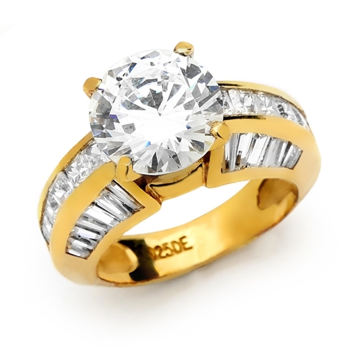 Diamond Essence Designer Ring with 3.50 Cts. Round Brilliant Center, set off by Chanel set Princess stones and Tapered Baguettes on either side.5.50 Cts. T.W. set in 14K Gold Vermeil.