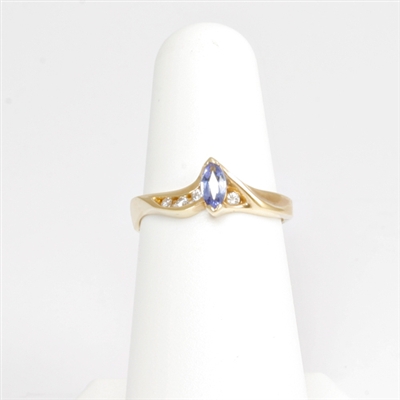 Lovely violet-hued marquise shaped tanzanite accented with channel set round brilliant cut diamonds in swirly 14K yellow gold ring.