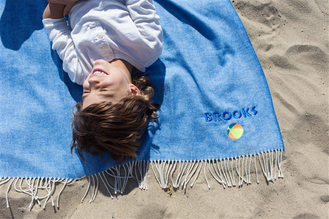 Adorable boy giggling on a blanket that is personalized with neon blue thread color and a neon beach ball graphic