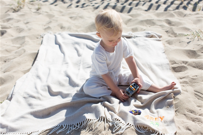 Adorable baby playing on the beach and laying on his personalized Blanket in Sand color with NEON personalization.