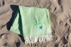 Lime Blanket laying on the beach personalized with neon green thread colors and a neon blue star graphic.
