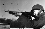 Photo of a GI firing a Tommy Gun from the World War 2 US Army training film Mastering the Thompson Sub Machine Gun.