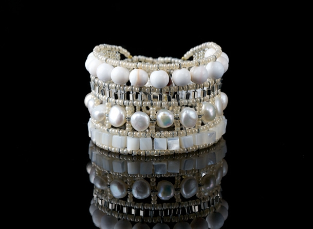 A stunning White on White Cuff Bracelet by Ziio.  Linear in design, it features a single row of White Mother of Pearl, White Fresh Water Pearls & White Agate Gemstones. Accented with Silver Beads. crafted on stainless steel wire with White Murano Glass