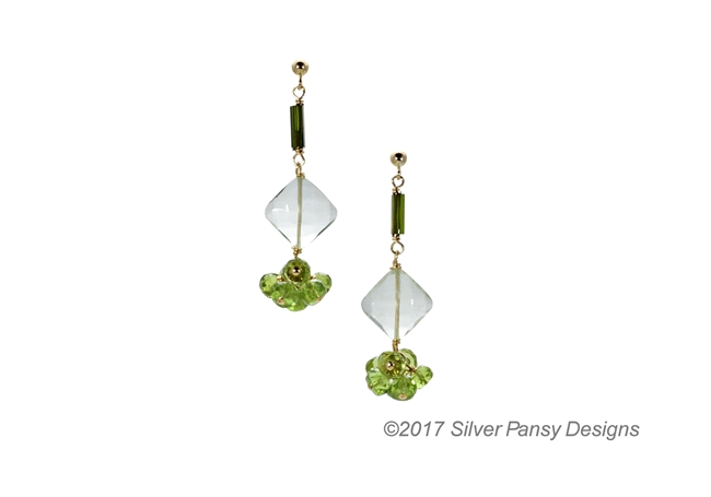 A unique drop Earring hand crafted in the U.S. by Silver Pansy. Dark Green Tourmaline beads lead the way with a diamond drop of soft Green Praisiolite, followed by a Green Peridot Gemstone. Gold Filled Sterling Silver wire & Posts.
