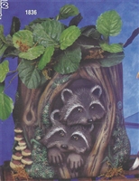 A large ceramic planter shaped like a tree stump. The base is dotted with small bits of greenery and a few mushrooms, and two small raccoons peer out of a hole in the stump. It has been filled with real greenery at the top.
