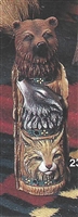 A cast ceramic statue of a small wooden "totem pole" of three animals. The base is a tan bobcat, looking forward. The middle a gray wolf, howling up. The top is the head of a brown bear, also looking forward.