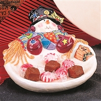 A cast ceramic dish shaped like a snowman. His head is at the dish top, and he wears a top hat, patchwork scarf, and mittens. The arms of the scarf come around the sides of his base, which serves as the dish. There is a small birdhouse at his side as well