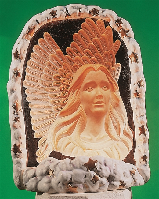 A cast ceramic piece depicting the bust of an angel surrounded by an arch and base of clouds and stars. A light placed within the piece illuminates it from behind. It has long flowing hair and looks forward, outstretched wings visible behind.