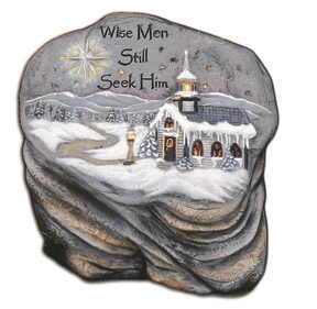 A large irregularly shaped cast ceramic slab textured to look like stone placed atop a large cast ceramic rock base. The slab features a snow-covered church in a snowy landscape. There is a shining star and the words Wise Men Still Seek Him in the sky.