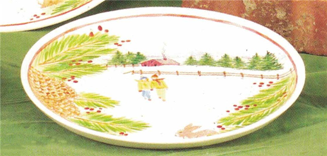 A simple round plate made of cast ceramic. It has been painted with a winter scene of a farmhouse and a walking pair of people among evergreen trees and holly bushes. There is a single thin red line around the border of the scene.