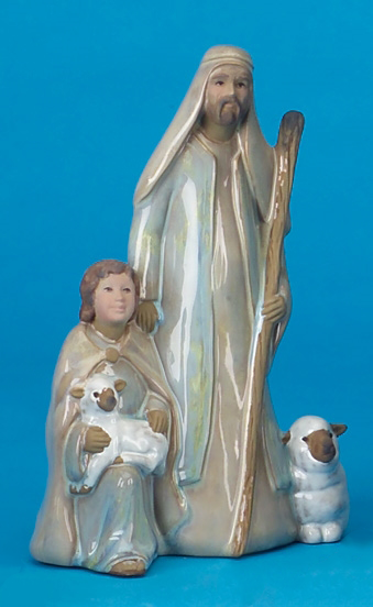 A cast ceramic figure of a tall shepherd with his arm on the shoulder of a kneeling shepherd boy to his right. The taller shepherd holds a walking stick and the kneeling boy has a lamb on his knee. A small sheep sits to the other side of the shepherd.