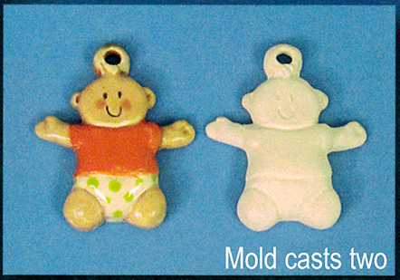 Two flat ornaments of cast ceramic. Both are shaped like a cartoon baby with dot eyes and outstretched limbs, wearing a shirt and diaper. There is a small ball with a hole in it atop its head for hanging. The left has been painted, the right has not.