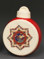 A spherical ornament made of cast ceramic. The front has been cut off to hold various disks. The disk shown has been decorated with an intricate decal and cut with small holes to allow light through. The ornament also has a decorative cap.