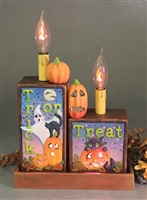 Two blocks set in a tray with small pumpkins on top. The left box is tall and thin, has a ghost, pumpkin, and cat, and reads â€œTrick or.â€ The right is short and wide, has a cat and pumpkin, and reads â€œTreat.â€ Both blocks hold candles.