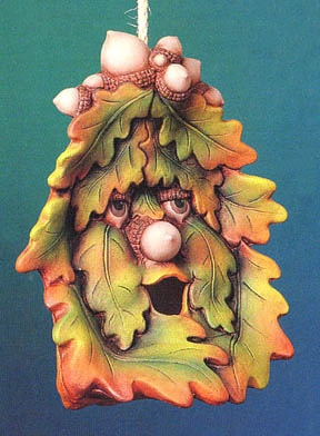 A cast ceramic piece suspended from a rope. It is shaped like an assemblage of maple leaves with a cartoonish face with acorn eyes and nose. The mouth is open, revealing a hollow interior. The piece is shaped overall somewhat like a house.