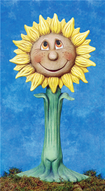 A cast ceramic figure of a tall, cartoonishly stylized sunflower. The center of the flower has a face with wide eyes, a round nose, and a large smile, as well as a scattering of freckles. It has two small petals like arms on its long stem.
