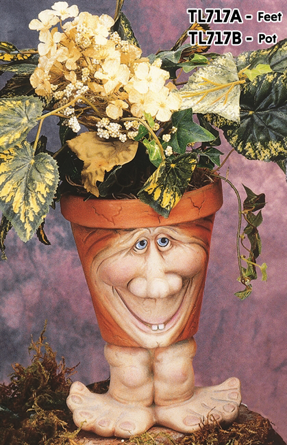 A cast ceramic pot with a cartoonish human face. The face has a large nose and round cheeks, and a large smile showing two teeth. The pot is textured with small lines like aged cracks and is placed atop wide cartoonish cast ceramic feet.