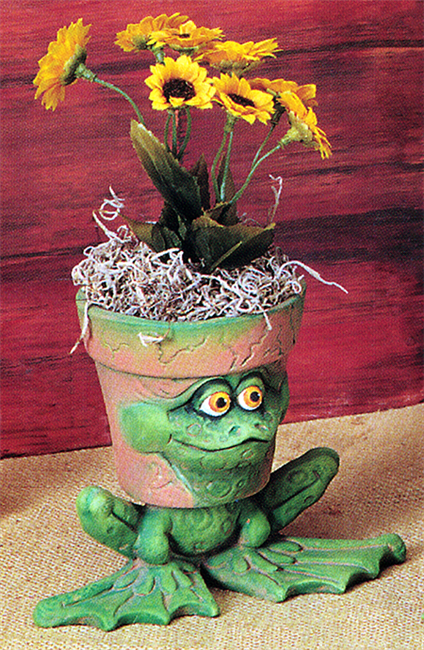 A cast ceramic figure of a cartoonish frog with its head as a functional pot. The body of the frog supports the head, seated with legs bent. Its face on the side of the pot looks forward intently. The pot has a few small lines like aged cracks.