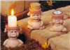 Three small, separate cast ceramic pigs, each with a head as a functional pot. The pigs are cartoonishly styled. The left sits, arms at its sides. The middle sits with arms wrapped around its belly. The right sits with its arms raised gleefully.